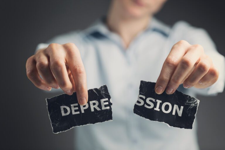 Woman holding a torn label with the word depression toward the camera.