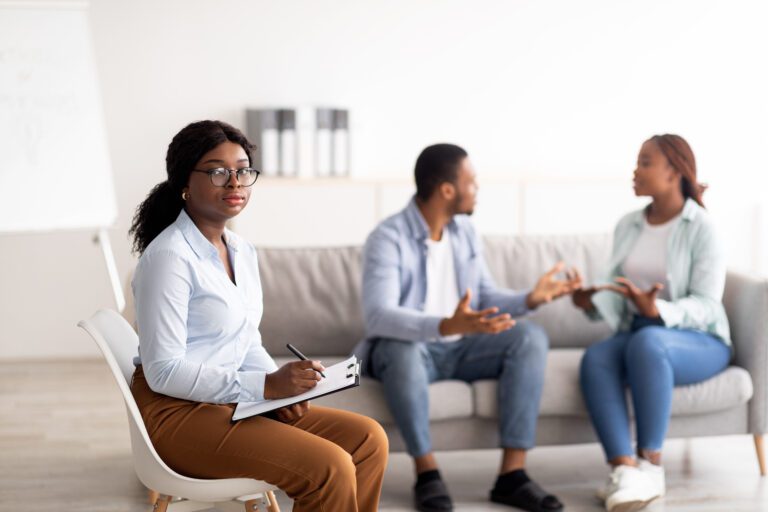 Female psychologist and young black couple having conflict during marital therapy at office,