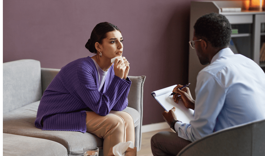 a woman sitting on a couch during a mental health therapy session with a therapist